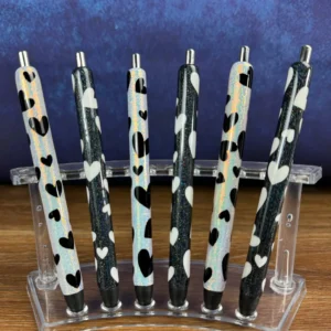 A set of seven pens in a holder.