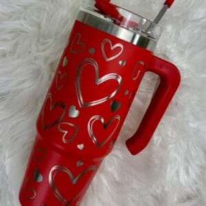 Red tumbler with heart designs and straw.