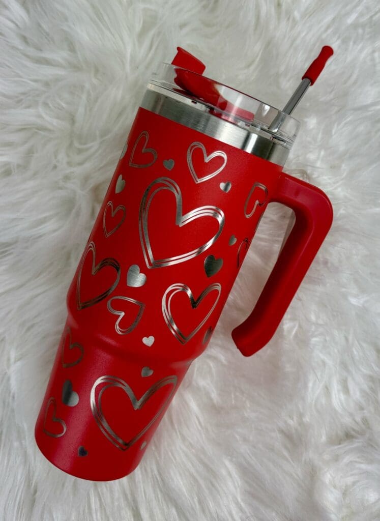 Red tumbler with heart designs and straw.