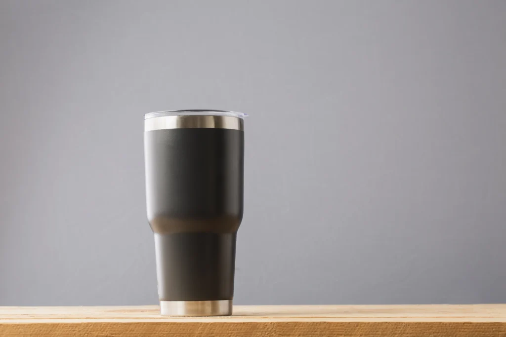 A black cup sitting on top of a wooden table.