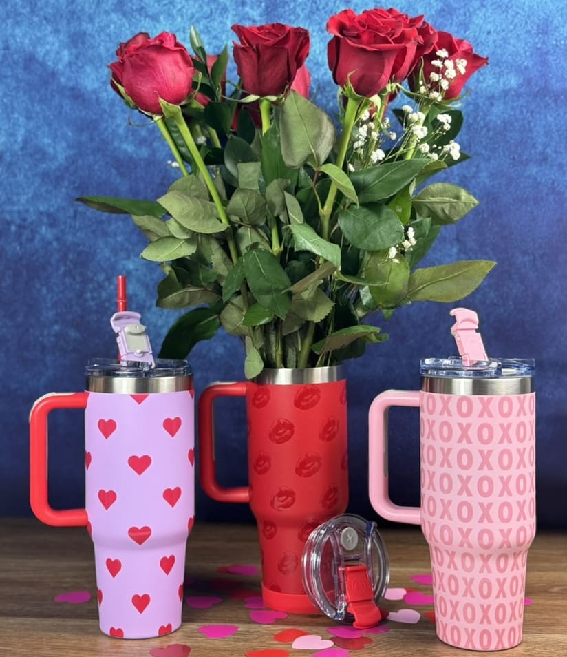 Flowers and festive mugs on wooden table.