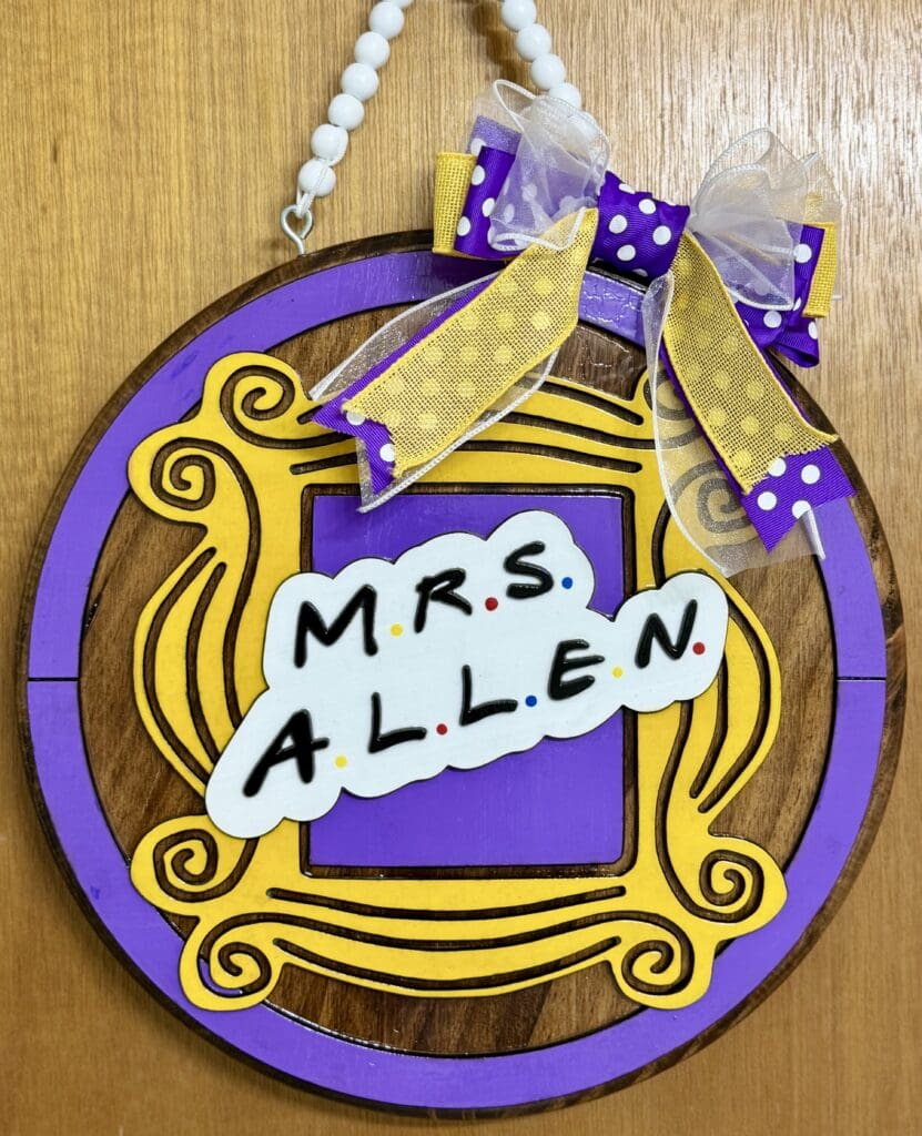 Purple and yellow decorative sign with bow.