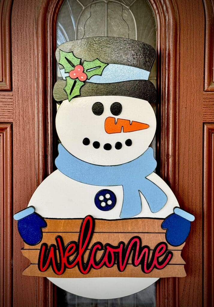 Snowman welcome sign on wooden door.