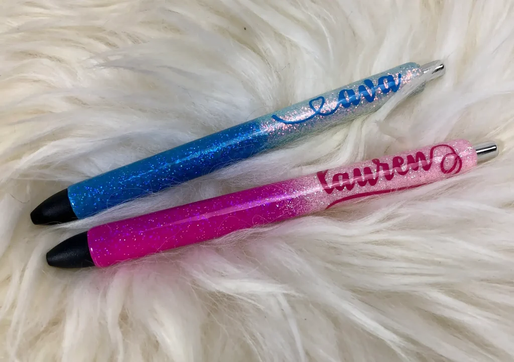 Two glittery personalized pens on white fur.
