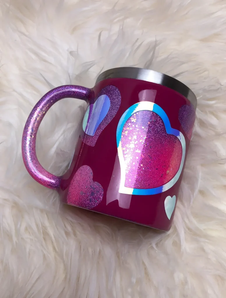 Colorful heart-patterned mug on fluffy surface.